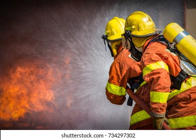 2 firefighters spraying high pressure water to  fire with copy space