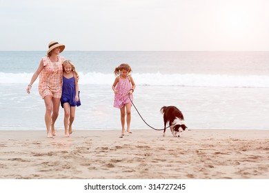 2 Girls Walking On Beach With Mom And Dog. Happy Family Walking.