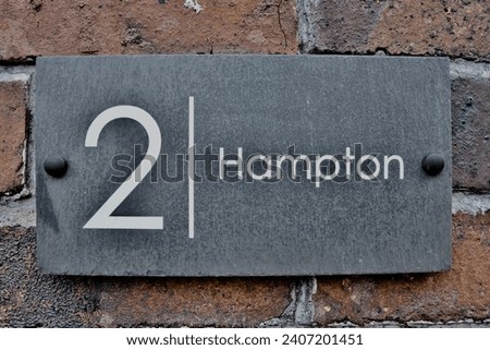 2 Hampton. Welsh slate door numbers and names on a victorian brick wall 