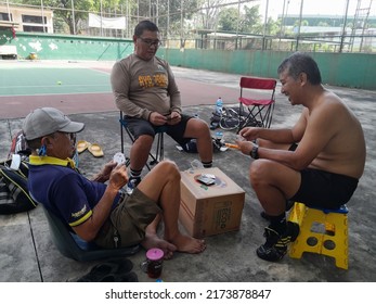 2 July 2022. Sidoarjo.Indonesia. Photo Of Three Happy Old Men, Playing Cards Together On The Edge Of A Tennis Court.