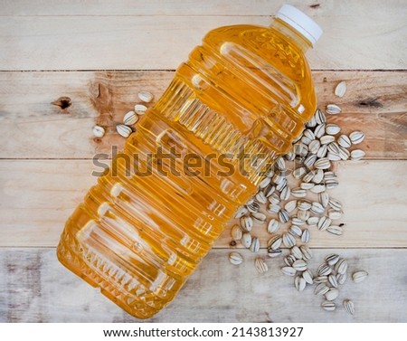 2 litre bottle of sunflower oil for cooking on raw wooden surface with sunflower seeds