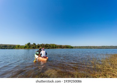 2 men rowing in a river with clear water