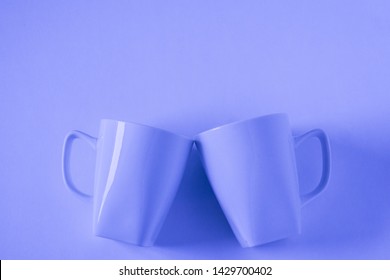 2 Monochromatic Blue Coffee Mugs On Blue Background Clinking In Cheers With Blank Empty Room Space For Text, Copy, Or Copyspace. Modern Top View Concept Of Two Cups With Solid Background Backdrop.