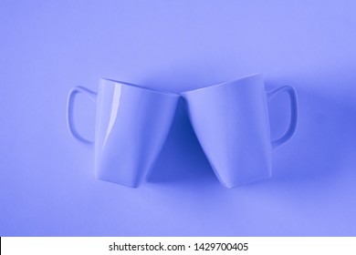 2 Monochromatic Blue Coffee Mugs On Blue Background Clinking In Cheers With Blank Empty Room Space For Text, Copy, Or Copyspace. Modern Top View Concept Of Two Cups With Solid Background Backdrop.