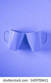 2 Monochromatic Blue Coffee Mugs On Blue Background Clinking In Cheers With Blank Empty Room Space For Text, Copy, Or Copyspace. Modern Top View Concept Of Two Cups With Solid Background Backdrop.