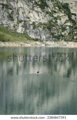 2 people seated on stand-up paddleboard makeing their way across the Lac d'Emosson hydroelectric power station dam reservoir in Switzerland