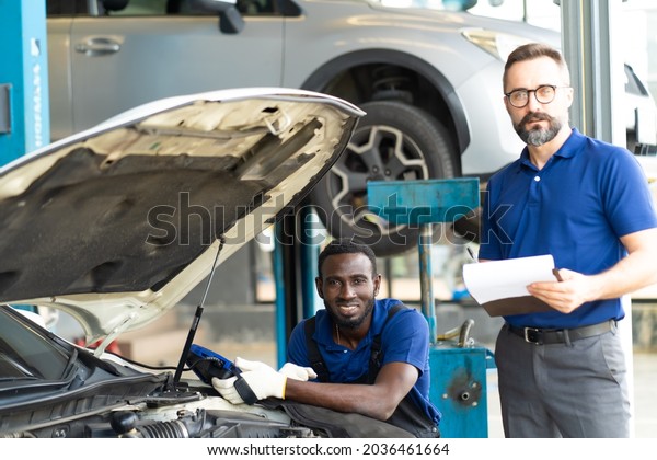 2 Professional car mechanic\
repair service and checking car engine by Diagnostics Software\
computer. Expertise mechanic working in automobile repair garage.\
