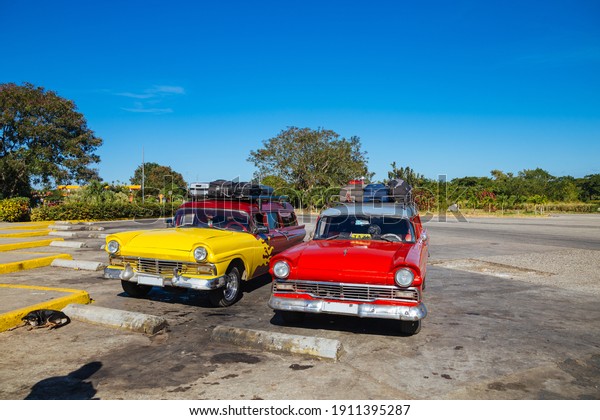 2 retro cars with luggage on the\
roof. Car in Cuba. Traveling by car in Cuba. Red retro car\

