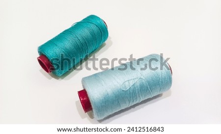 2 rolls of sewing thread with blue and tosca coulour and white background