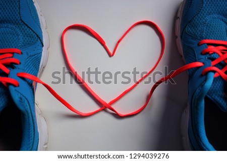 2 running shoes with laces entwined into a heart