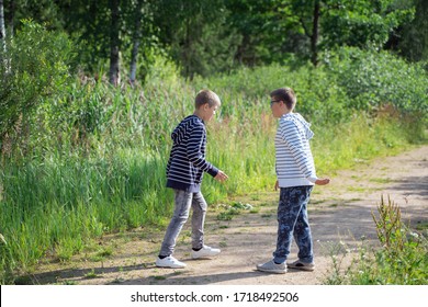 2 school-age brothers age quarrel on a walk in the woods on a sunny summer day