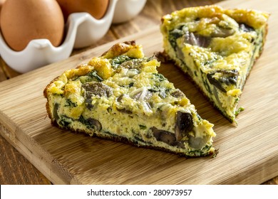 2 Slices Of Spinach Mushroom And Egg Frittata Sitting On Wooden Cutting Board