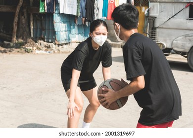 2 teenagers play 1 on 1 street basketball at a makeshift open court in a poor neighborhood or slum area. - Powered by Shutterstock