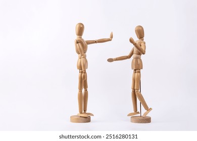 2 wooden mannequins representing an arguing couple, one of them making stop gesture with hand, isolated on white background. Copy space. Concept of discussion and conflict - Powered by Shutterstock