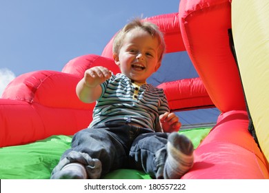 2 year old boy jumping down the slide on an inflatable bouncy castle - Shutterstock ID 180557222