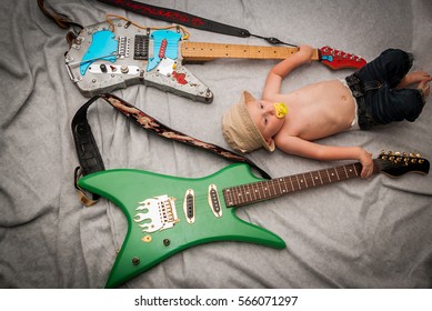 2 Year Old Boy Without A Shirt, Laying Down With His Mom And Dad's Electric Guitars.