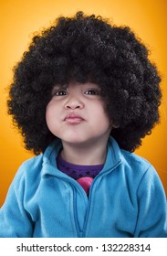 2 year old girl with an afro wig, making pout.