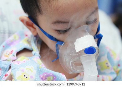 2 Years Old Asian Toddler Boy Has Asthma Or Pneumonia Disease And Need Nebulizations,Sick Boy Rest On Patient Bed And Has Inhalation Therapy By The Mask Of Inhaler.Sick Or Cancer Child Awareness. 