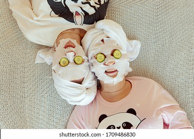 2 Young women wrapped hair with towel while having fun with homemade facial mask. Beauty treatment process of aging for rejuvenation, Skin Restoration Whitening, Moisturizing, Brightening.