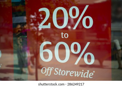 20% to 60% off store-wide red sign in shop window. Red sign with white writing. Shop window reflects street.  - Shutterstock ID 286249217