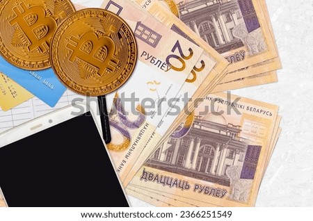 20 Belorussian rubles bills and golden bitcoins with smartphone and credit cards. Cryptocurrency investment concept. Crypto mining or trading transactions