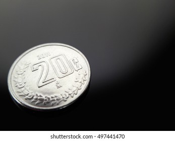20 cents, Mexican currency on glossy dark surface.
