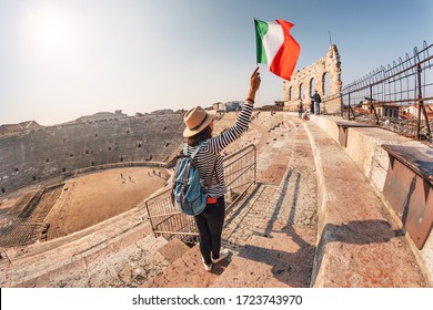 20 October 2018, Verona, Italy: girl holds an Italian flag standing on the steps of an ancient Roman amphitheater. The concept of uniting Italy in the face of a pandemic and lockdown