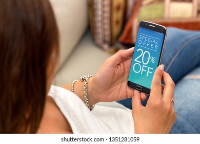 20 Off Promotion, Special Offer In A Cell Phone. One Young Woman In Her Home Resting In Sofa Holding A Smartphone With A Advertising 20% Off  In The Screen.