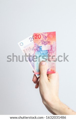 20 PLN and 20 CHF banknotes held in hand.