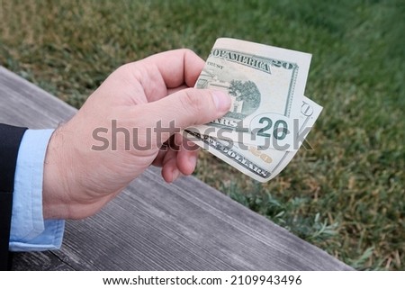 20, twenty dollar bill in the hand of a man in a business suit. The concept of cash, payment without terminals