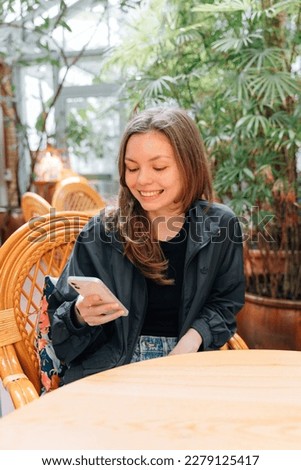 20 years old woman using phone in tropical restaurant