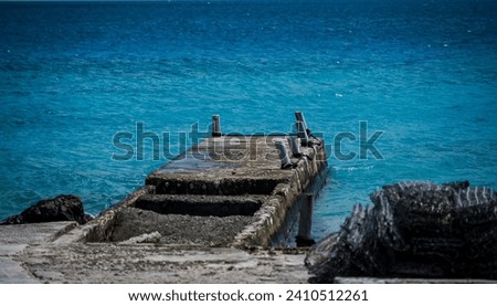 A 200mm telephoto shot of an old  pier jutting into the aqua waters around  Rangiroa in French Polynesia