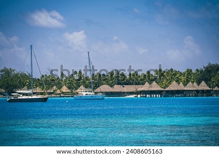 A 200mm zoom photo of anchored sailboats and thatched huts off the coast of  French Polynesia