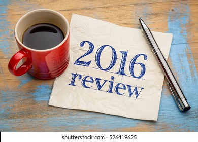 2016 review text on a napkin with coffee against grunge wood desk