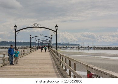 2016-April-24: People take a casual stroll on the White Rock Pier located at White Rock Promenade British Columbia Canada on a gloomy day