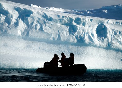 2017 May. Antarctica. Boat Of Researchers In The Icy Sea With Iceberg In The Background, In Sunny Day In Antartica.