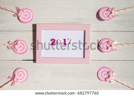 2017 in pink frame. Candy, top view flat lay on white wood background. Sweet , lollipop, candy