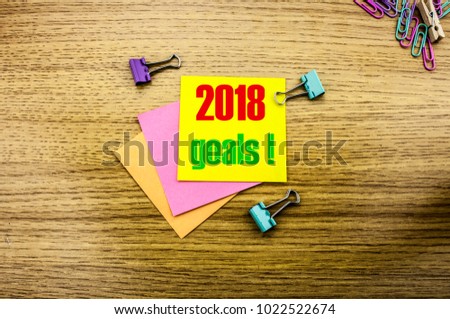 2018 goals on yellow sticky note, on wooden background. New Year resolutions concept. Goals 2018 concept.