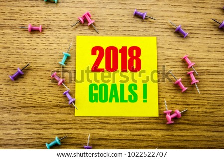 2018 goals on yellow sticky note, on wooden background. New Year resolutions concept. Goals 2018 concept.