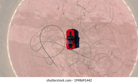 2019 August, Dubai. Aerial view Red race car riding on the desert road in UAE.