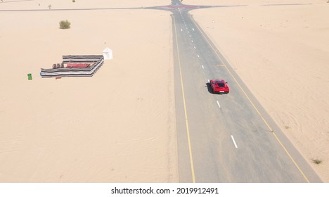 2019 August, Dubai. Aerial View Red Race Car Riding On The Desert Road In UAE.