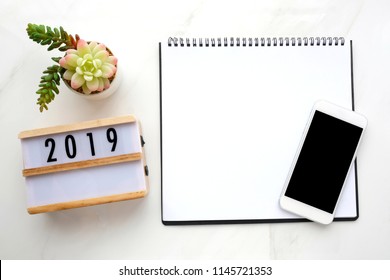 2019 goal resolution for new year, Blank note book paper, smart phone with blank screen on white marble background, 2019 new year mock up, template, flat lay