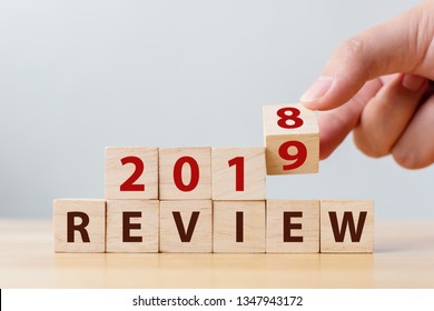 2019 review concept. Hand flip wood cube change year 2018 to 2019 and the word REVIEW on wooden block on wood table