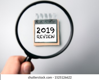 2019 review concept. Man's hand, holding magnifying glass