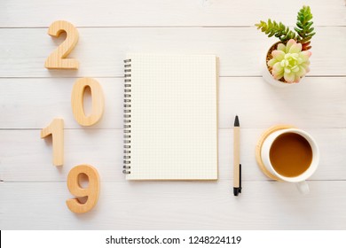 2019 wood letters, blank notebook paper and coffee on white table background, 2019 new year mock up, template with copy space for text, top view