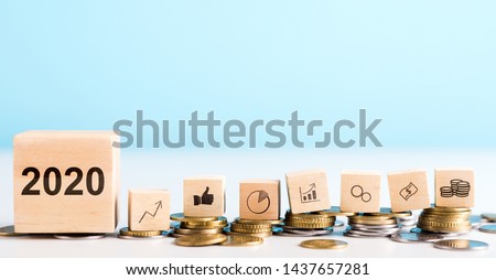 2020 concept. Government economy improvings. Wooden blocks with coins, dollar, graphs laying on real money, panorama, copy space