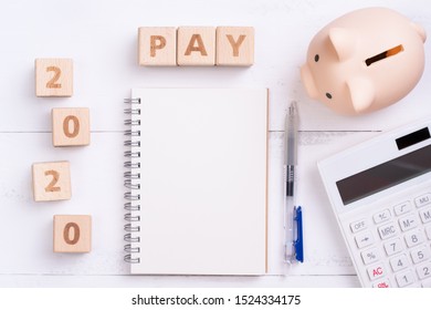2020 goal, finance plan abstract design concept, wood blocks on white table background with piggy bank and calculator, top view, flat lay, copy space.