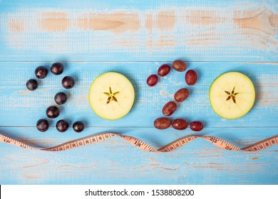 2020 Happy New Year And New You With Fruits, Black Grapes, Red Grapes And Green Apples On Blue Wood Background. Goals, Healthy, Healthcare, Resolution, Time To New Start, Fitness And Dieting Concept.