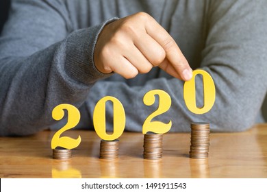 2020 New Year Saving Money And Financial Planning Concept. Female Hands Putting Gold Wooden Number 2020 On Stack Of Coins. Tax Payment, Investment And Banking.