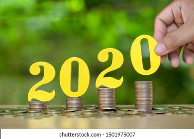 2020 New Year Saving Money And Financial Planning Concept. Female Hands Putting Gold Wooden Number 2020 On Stack Of Coins. Tax Payment, Investment And Banking.